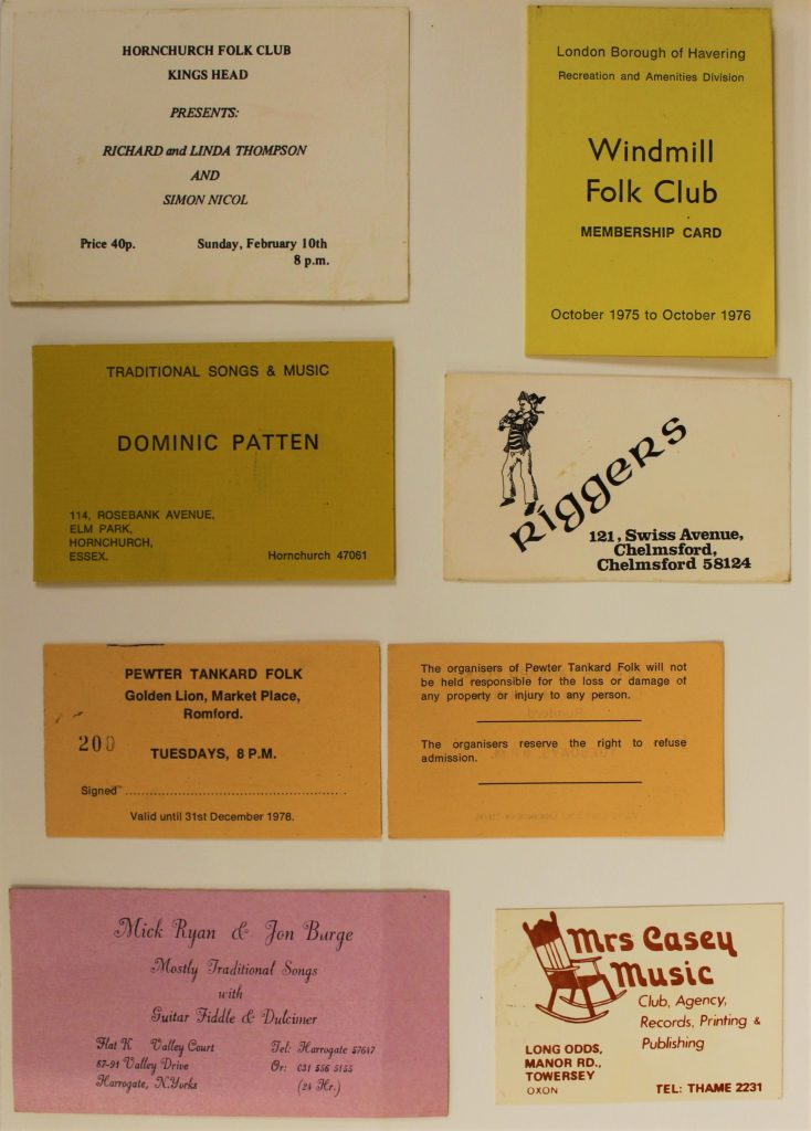Membership cards for folk clubs in Essex and cards for musicians and others involved in the folk scene, laid on a table. Most feature black stylised text on cream, yellow, orange or pink backgrounds. 