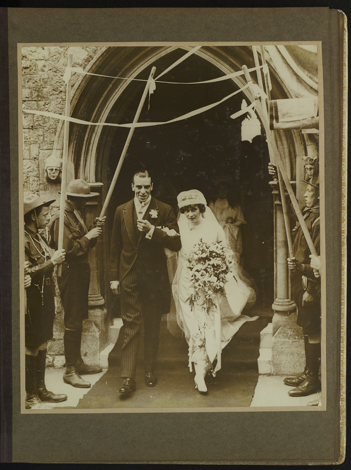 Black and white photograph of bride and groom leaving the church with scouts as guard of honour