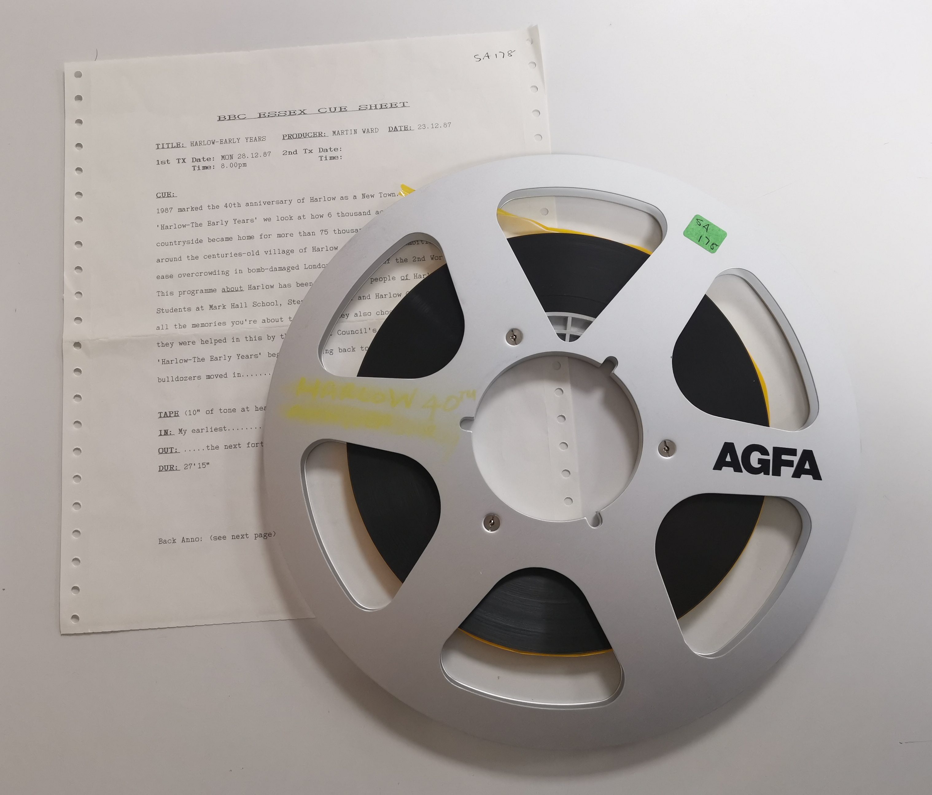 Image from above of AGFA tape reel, on top of paper BBC Essex cue sheet.