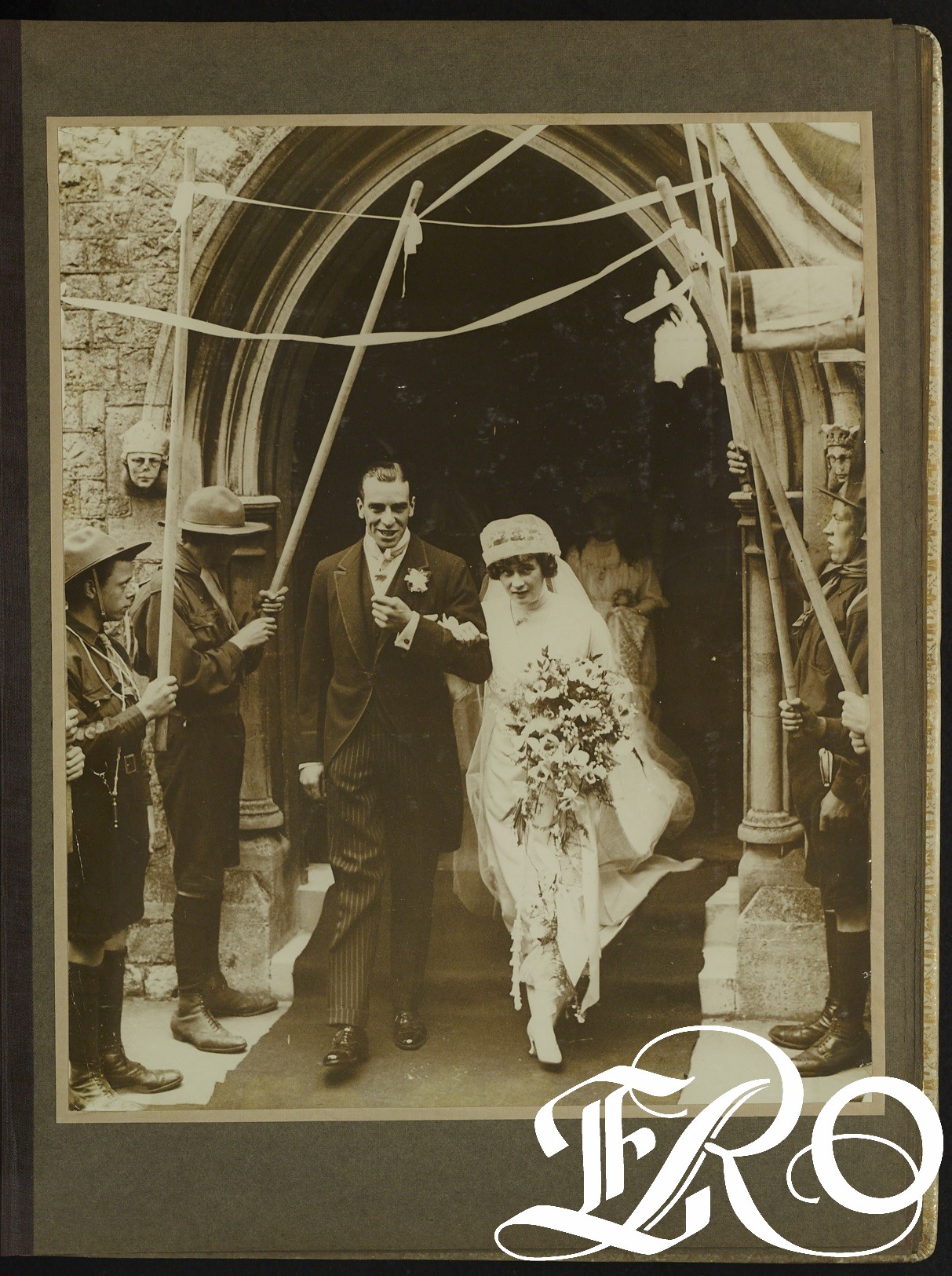 Black and white photograph of bride and groom leaving the church with scouts as guard of honour