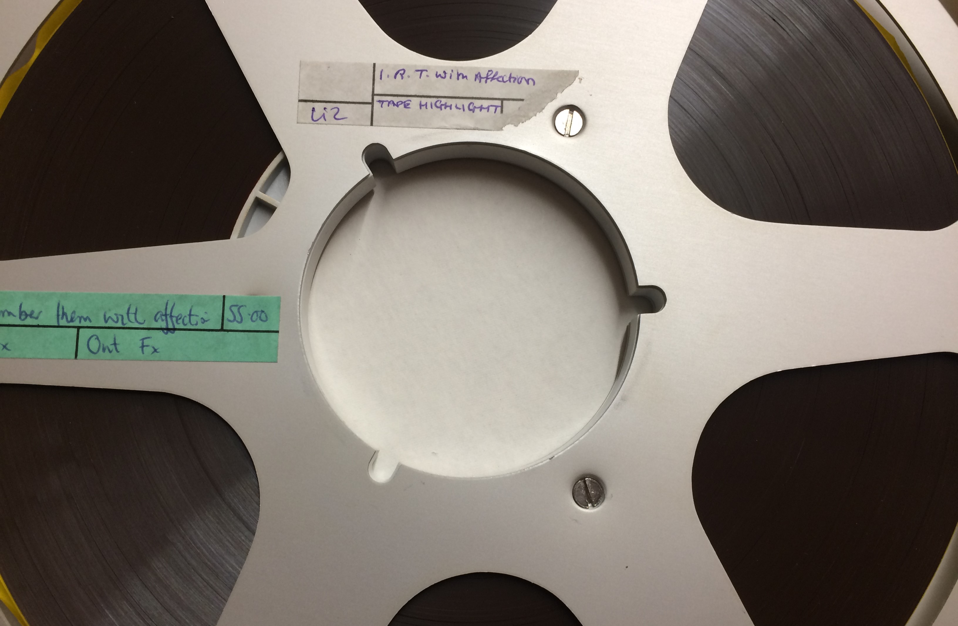Photograph of silver tape reel with black magnetic audio tape. Two handwritten labels read 'I remember them with affection'.